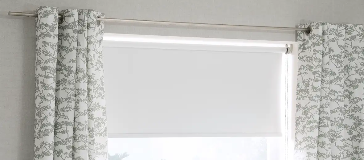 Rollo in weiß vor Fenster, leicht geschlossen. Vorhänge in grün-weißem Muster links und rechts daneben