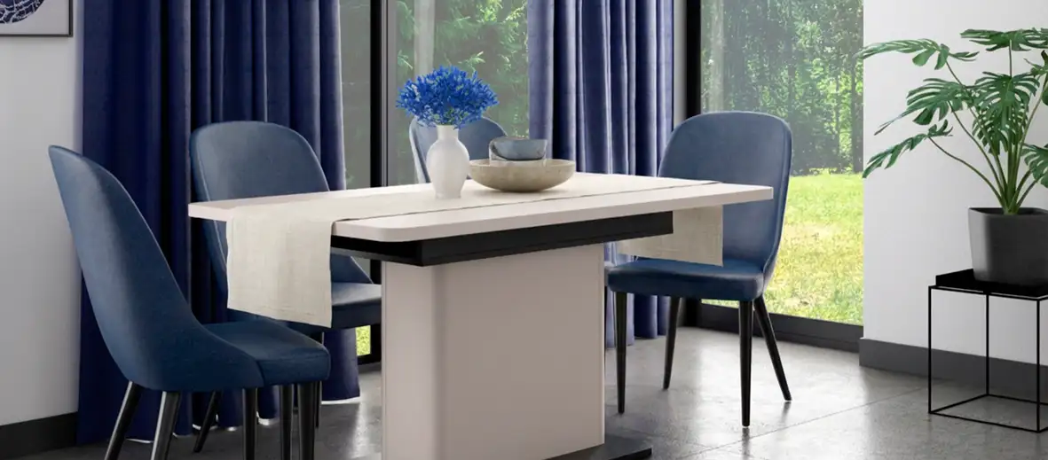 Beiger Esstisch mit beigem Tischläufer, daneben Stühle in dunkelblau. Auf dem Tisch eine weiße Vase mit blauen Blumen