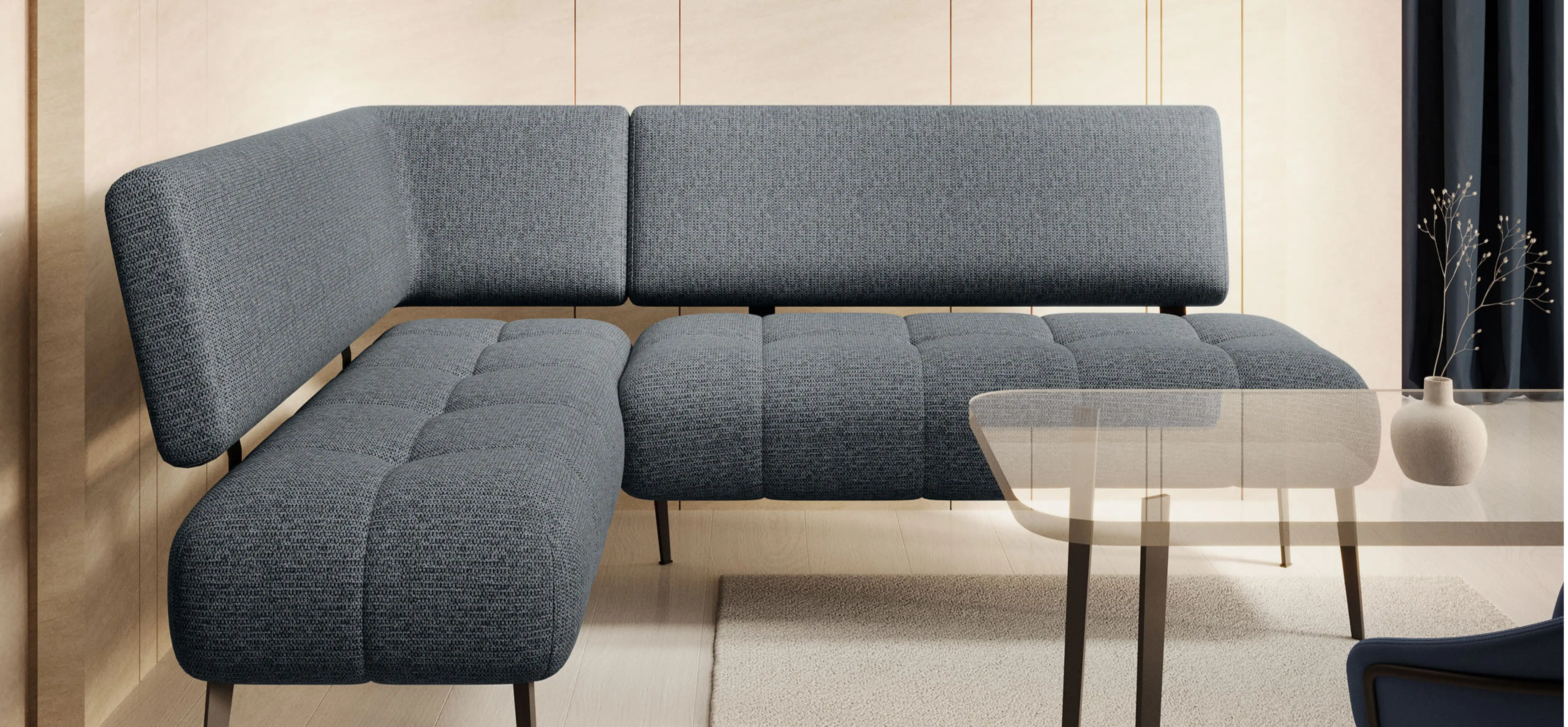 Eckbank aus grauem Polster mit Rückenlehne. Glastisch mit dunklen Beinen davor