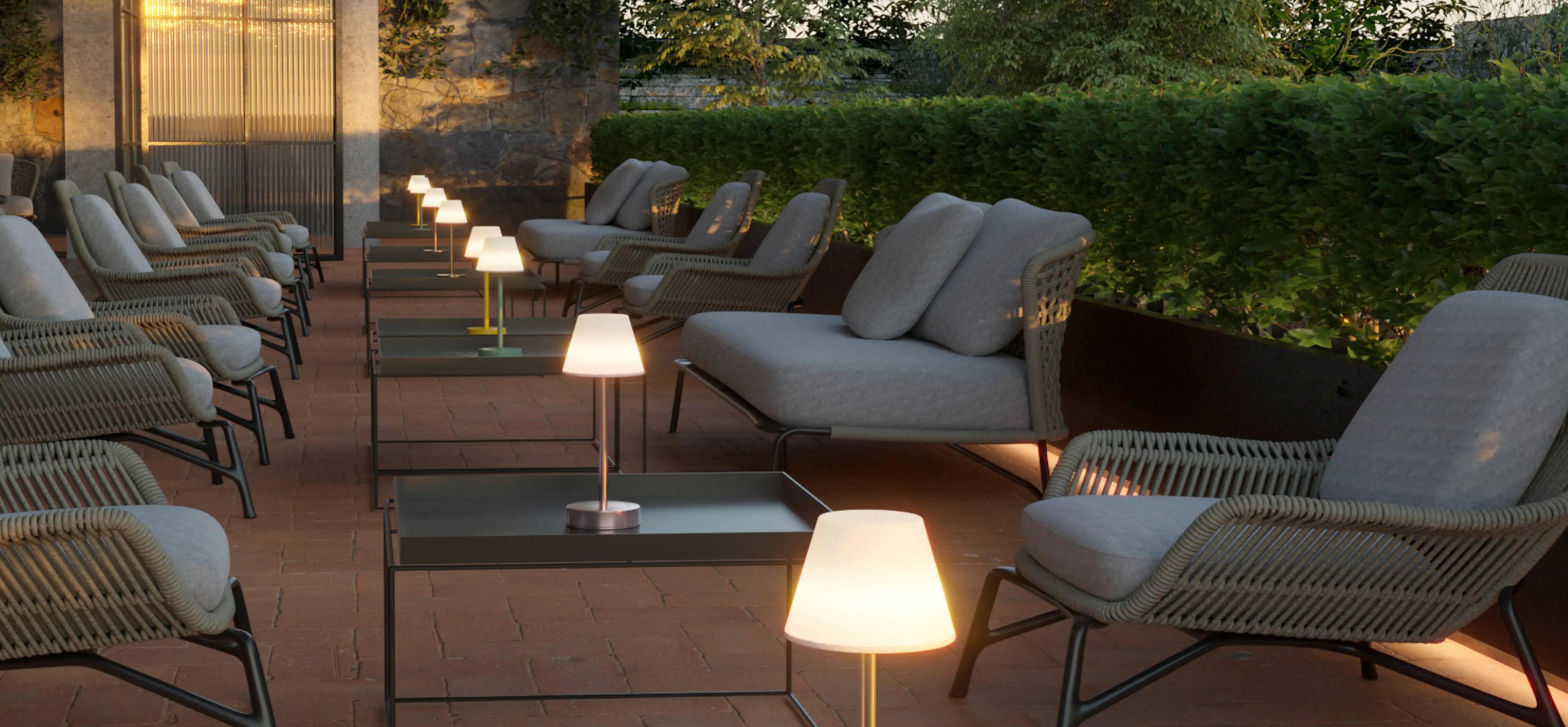 Sitzgruppe auf Terrasse mit grauen Sesseln und schwarzen Beistelltischen. Tischleuchten auf den Tischen